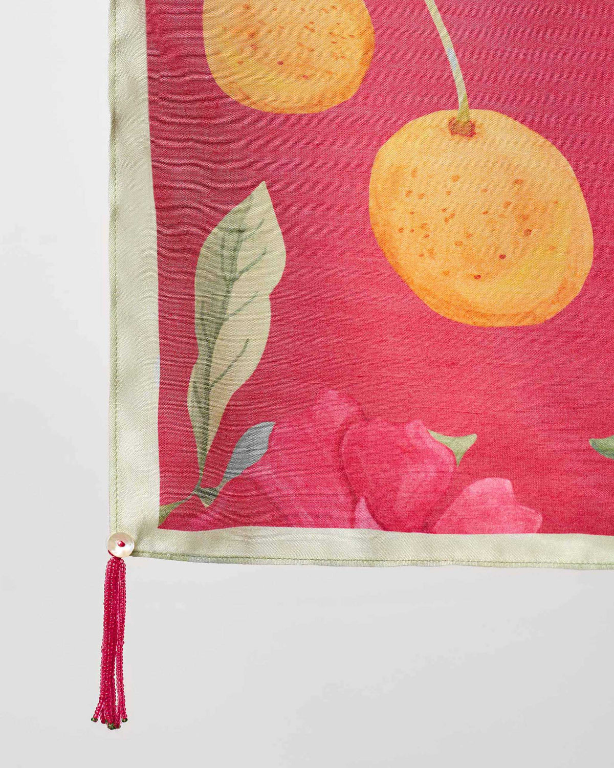 Close-up of a Dusk Garden scarf corner showing orange fruit and a pink flower.