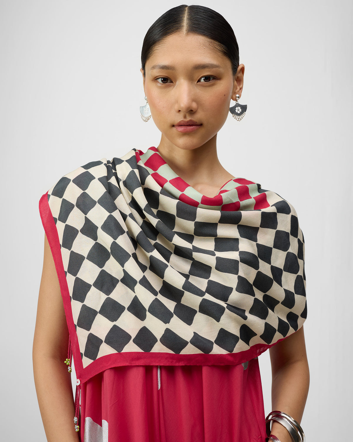 Person wearing an ivory and charcoal Nura scarf with a red border.
