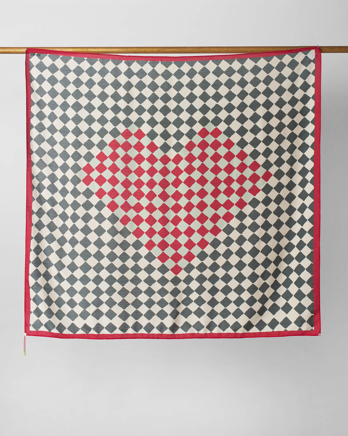 Nura scarf hung flat, showing a red diamond motif on charcoal and ivory.