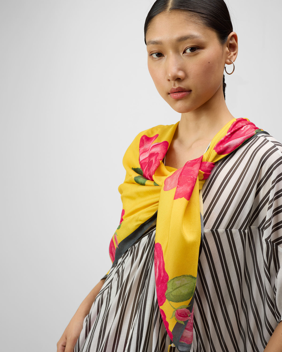 Person wearing a yellow Kesar scarf with a pink rose print.