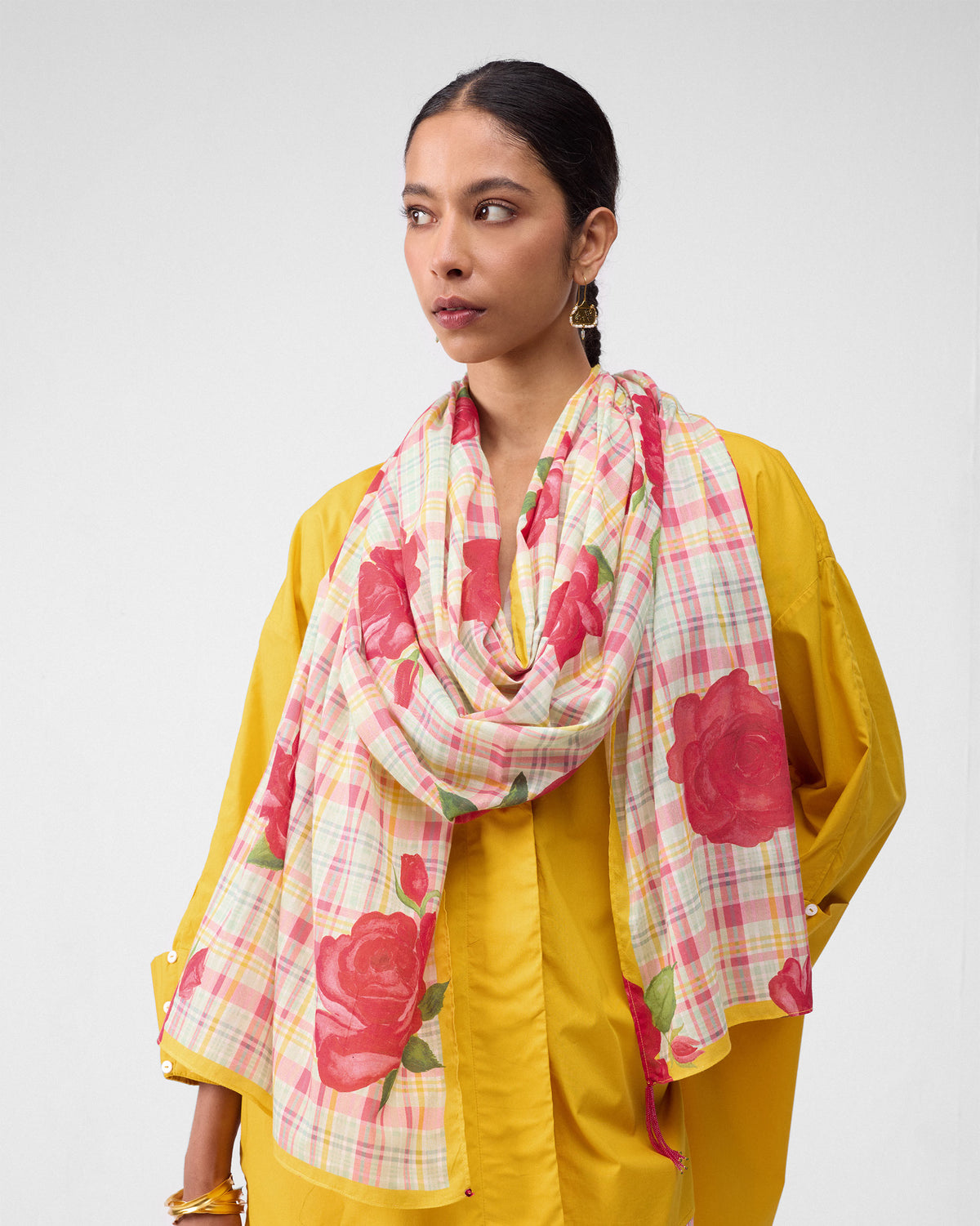 Person wearing a Ruhm scarf with large red roses on a pink and yellow check.