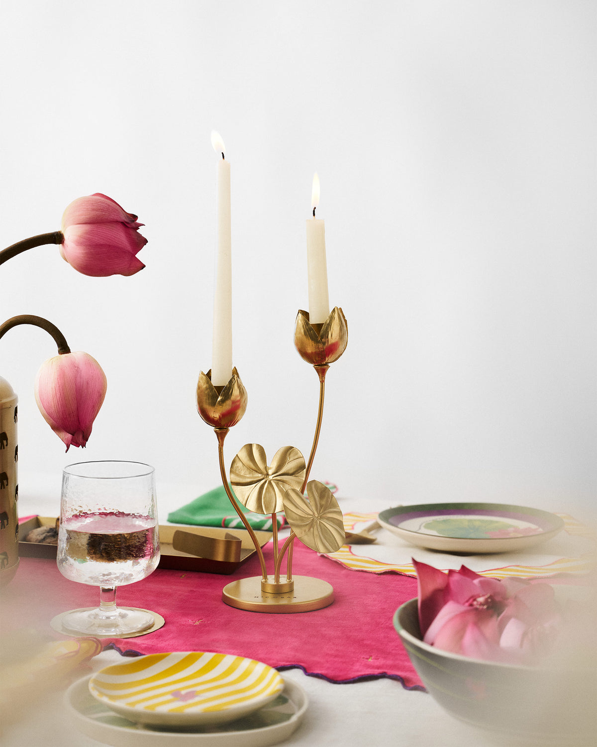 Island Lotus candle holder with two lit tapers on a dining table.