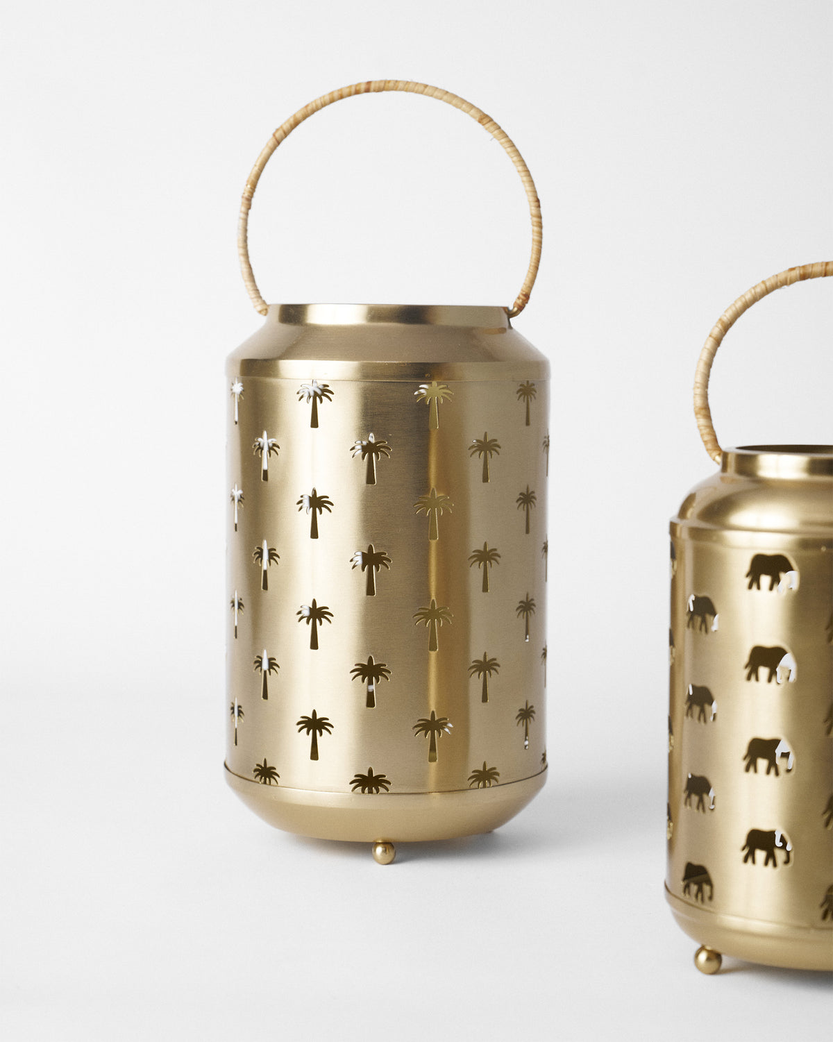 Gold Ele Palm lantern with palm cutouts and a rattan handle.