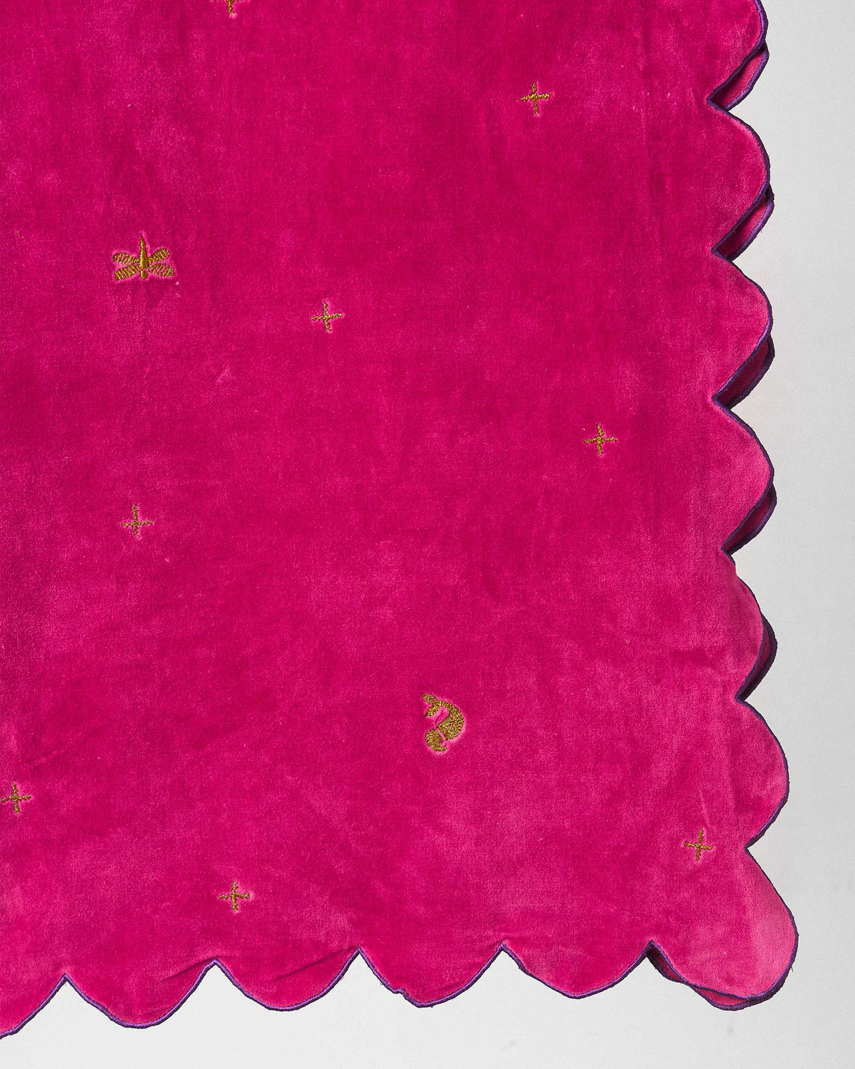 Close-up of a Dream table runner showing its scalloped edge and gold motifs.