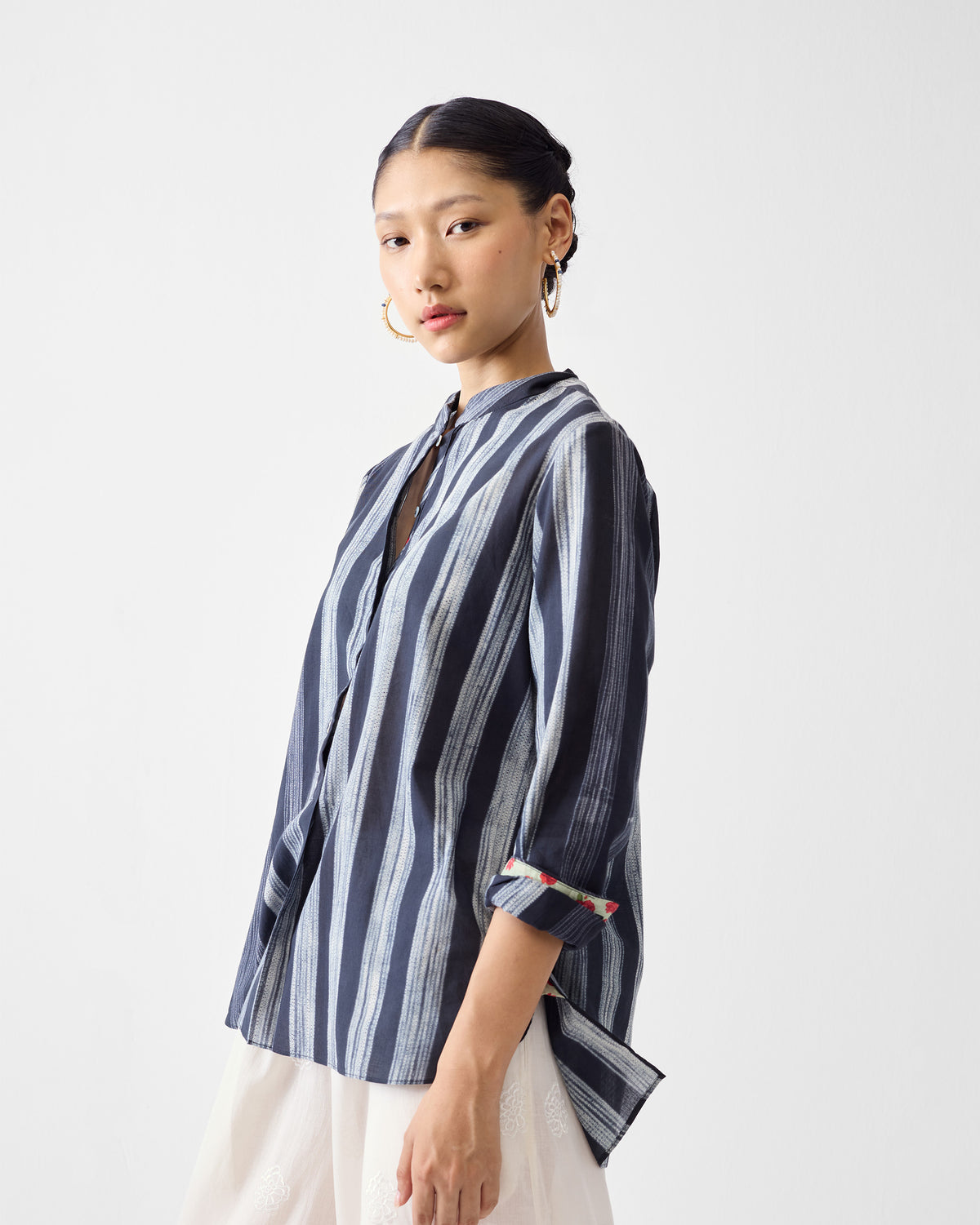 Side view of a charcoal and ivory striped mandarin collar top with rolled sleeves.