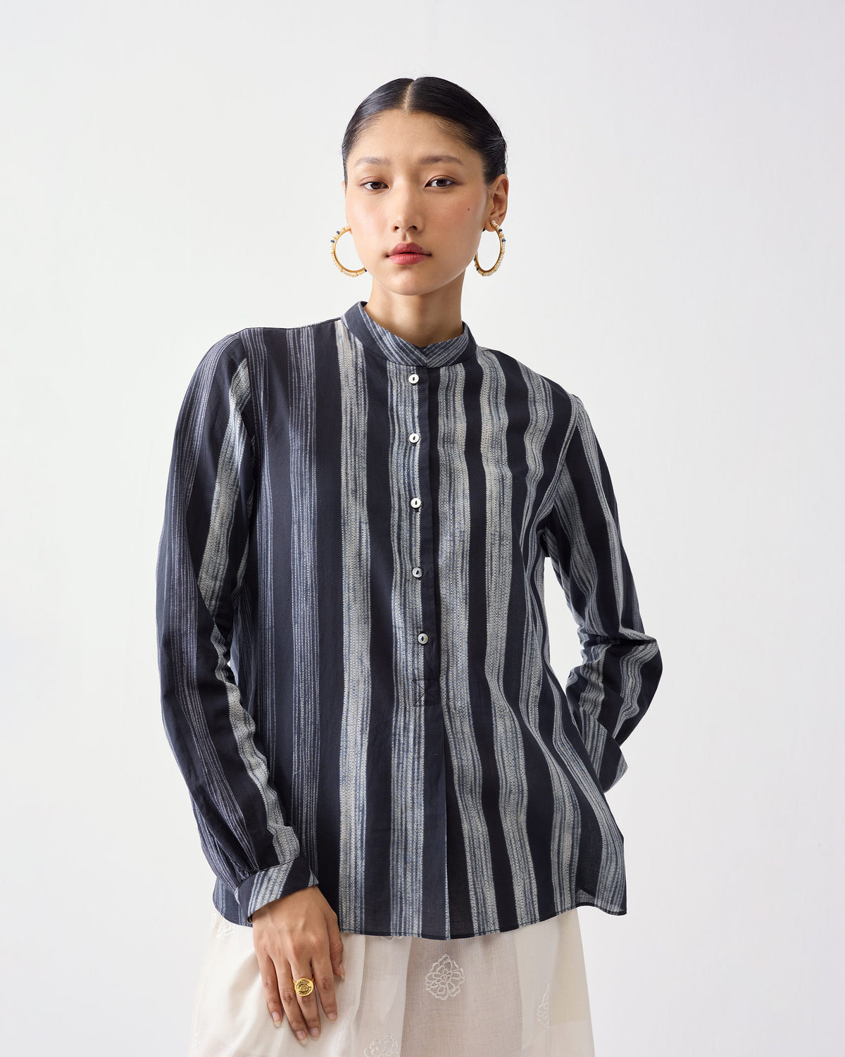 Person wearing a charcoal and ivory striped mandarin collar top with sleeves down.