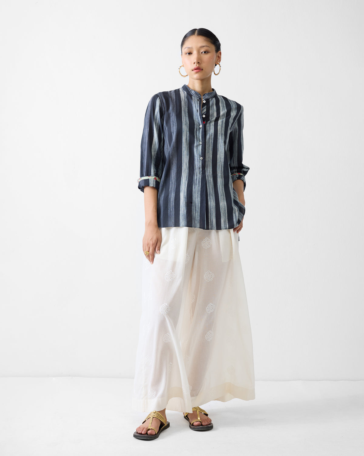Person wearing a charcoal and ivory striped mandarin collar top.