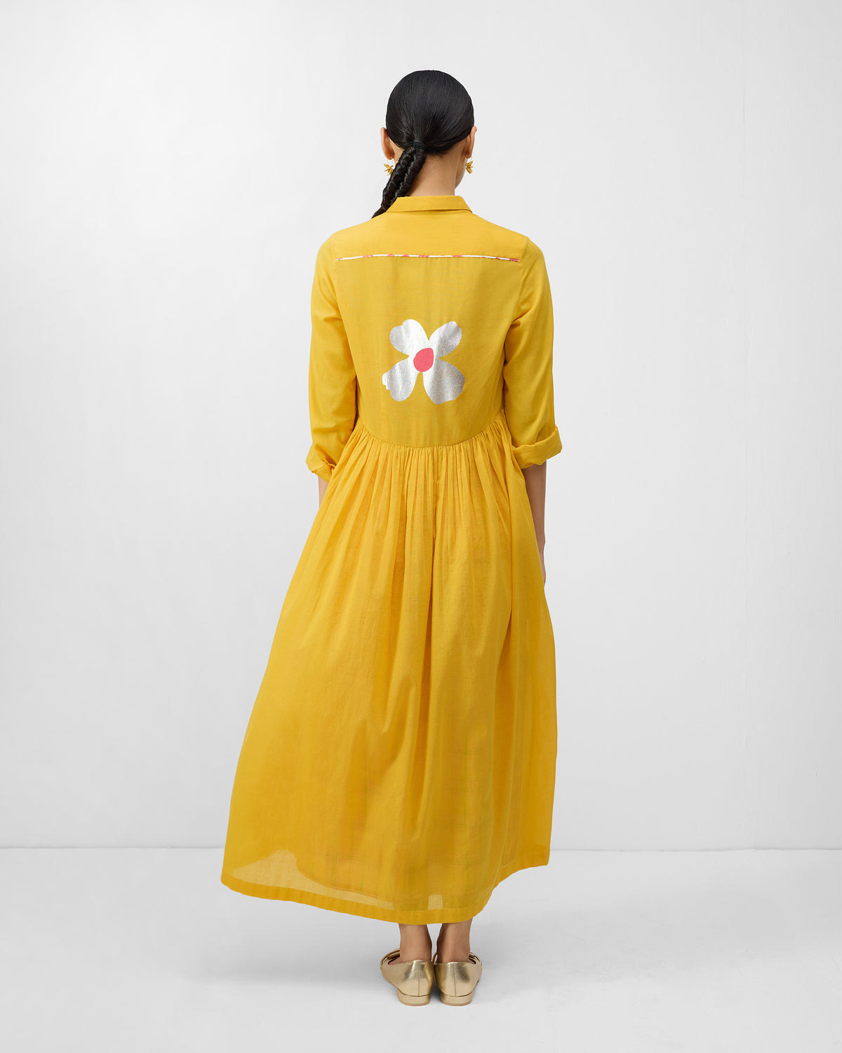 Back of an Aurora Dress in turmeric yellow with a large silver flower.