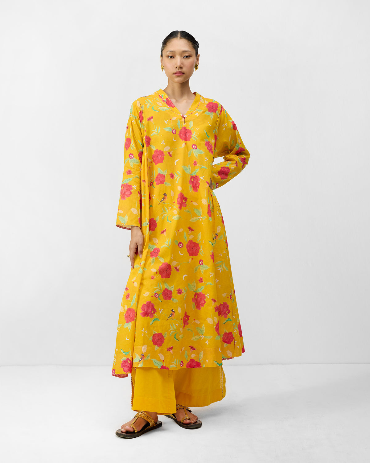 Person wearing a turmeric yellow Amreli kurta with floral and bird print.