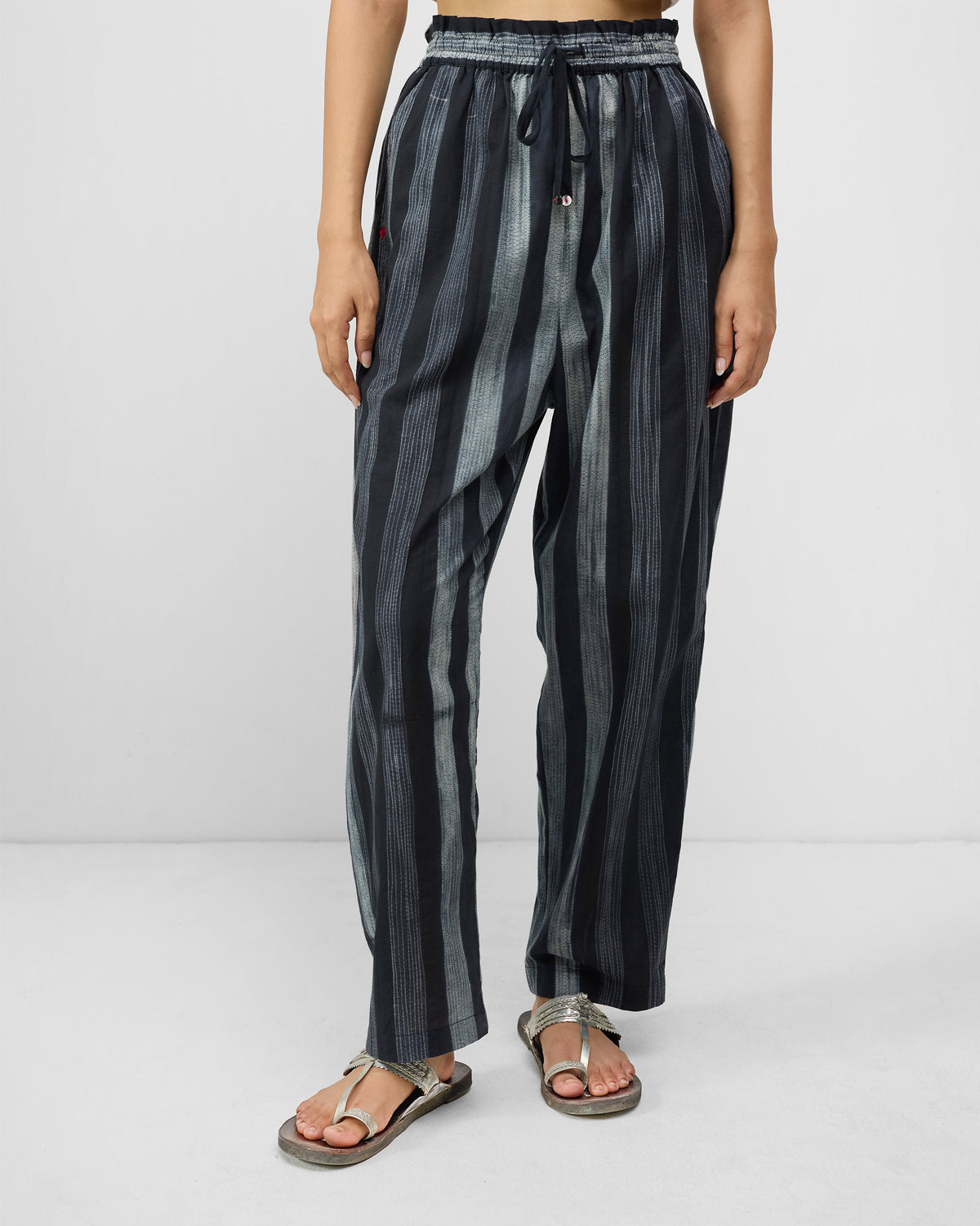 Person wearing charcoal and ivory striped Areca Pants with a drawstring waist.