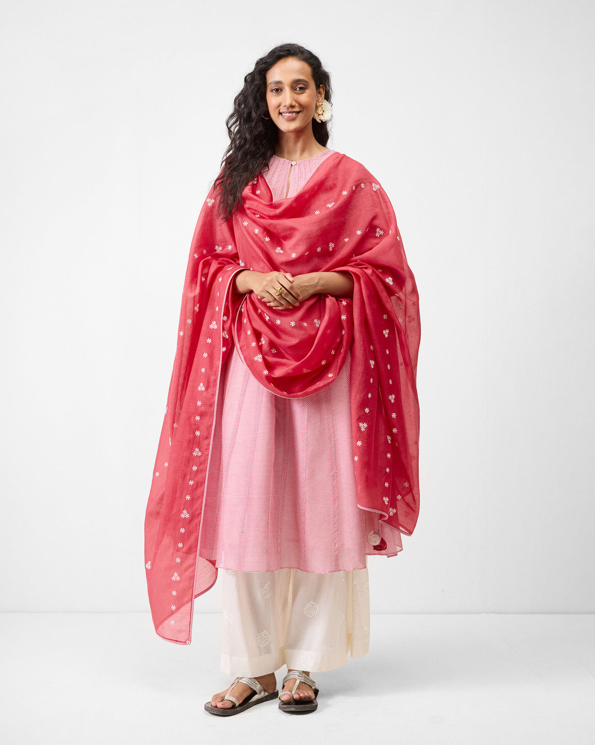 Person wearing a pink Pattaya kurta with a red wrap draped over it.