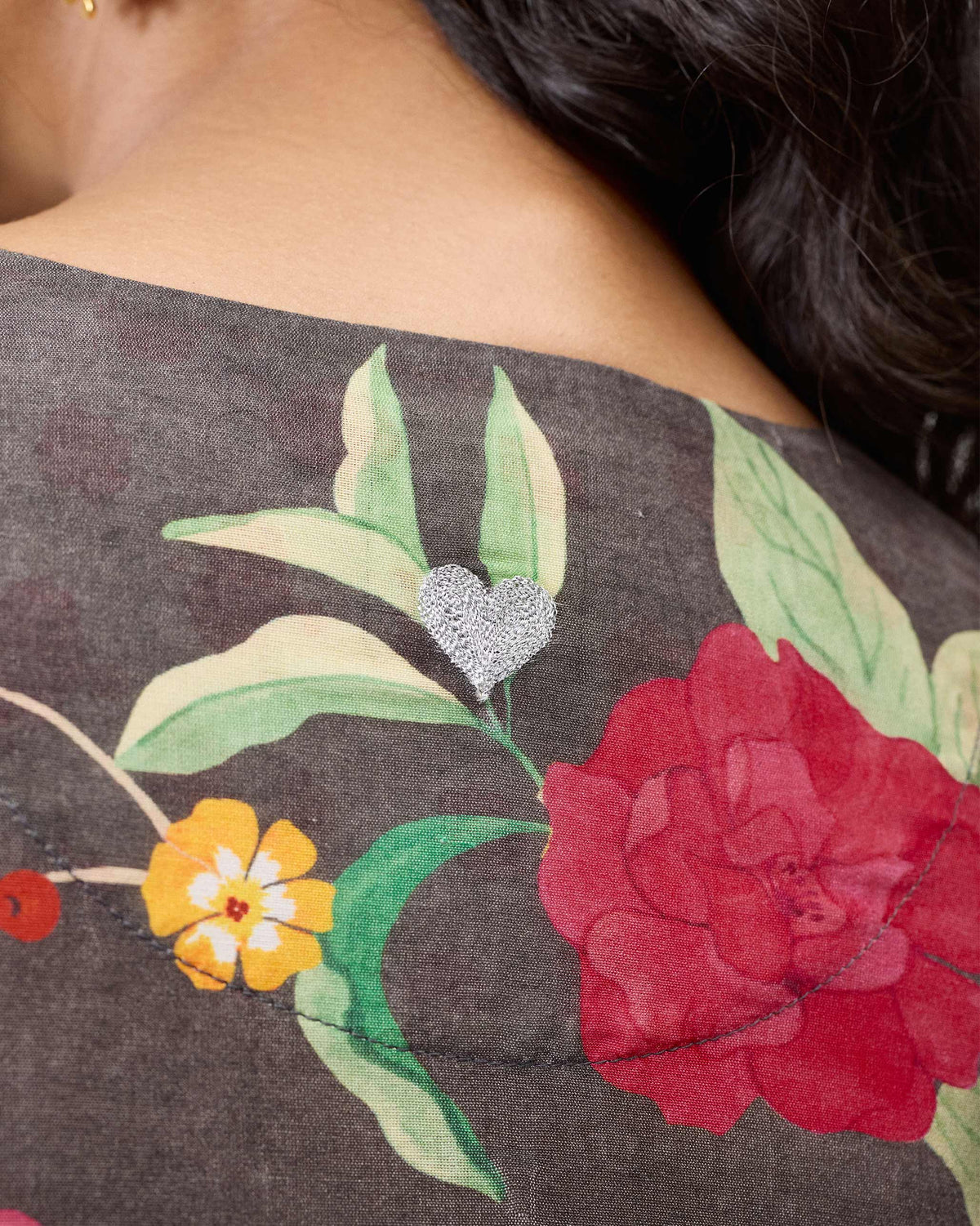 Close-up of a charcoal floral kurta with a silver heart at the neck.