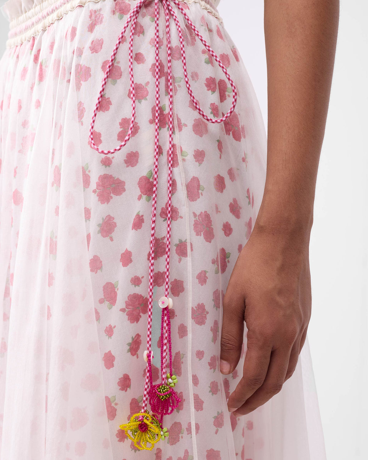 Close-up of a Pushkar skirt waist with a gingham drawstring and beaded flower tassels.
