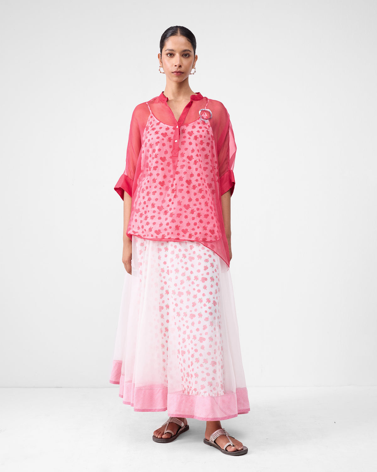Person wearing an ivory and watermelon Pushkar skirt with a sheer overlay and pink hem.