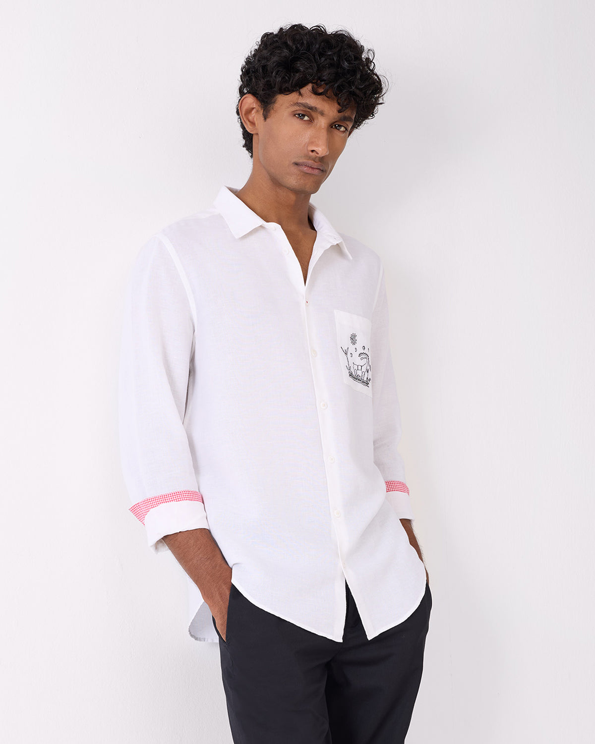 Person wearing a white Musafir Pocket Shirt with pocket embroidery.