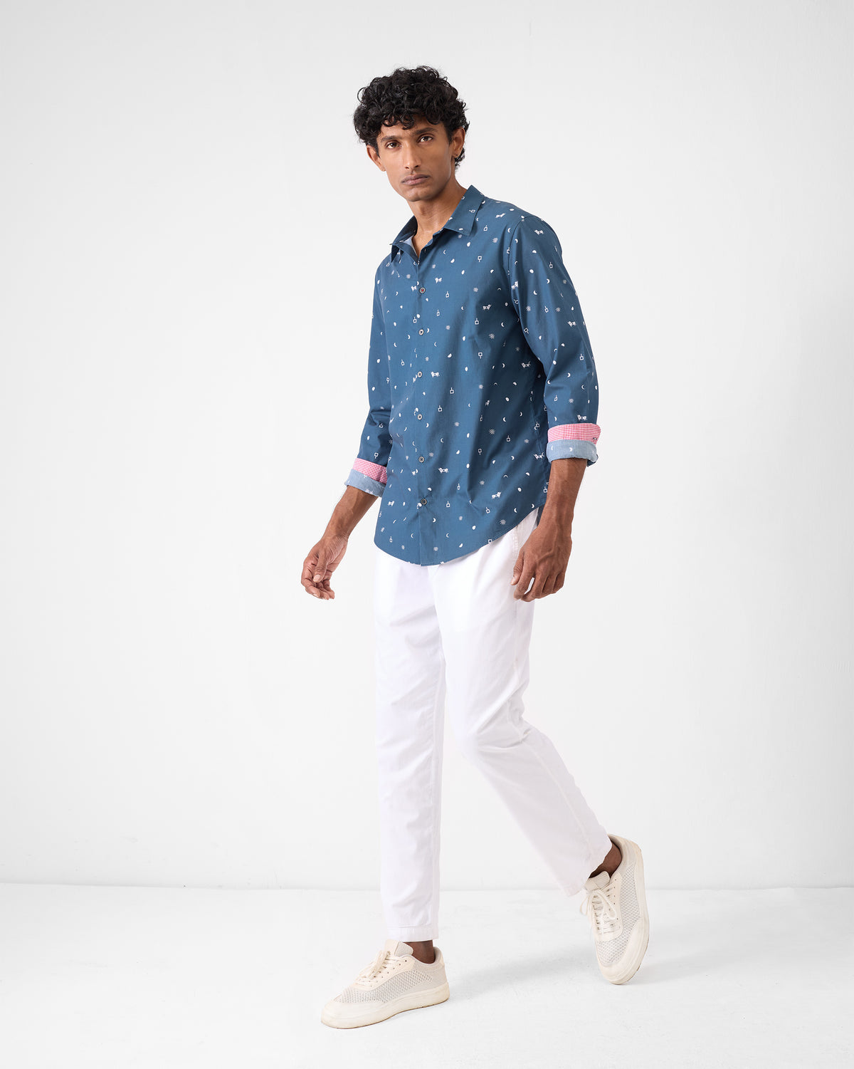 Person wearing a navy Hakuna shirt with pink cuff lining over white trousers.