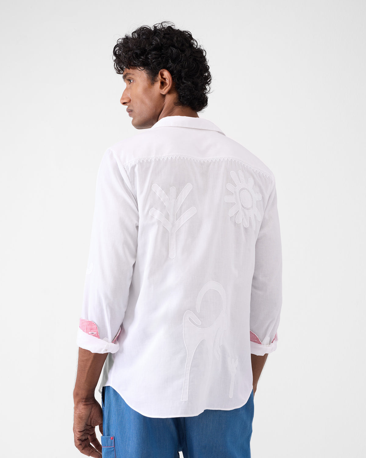 Back of a white Hakuna Shirt with tonal appliqués and gingham cuff lining.