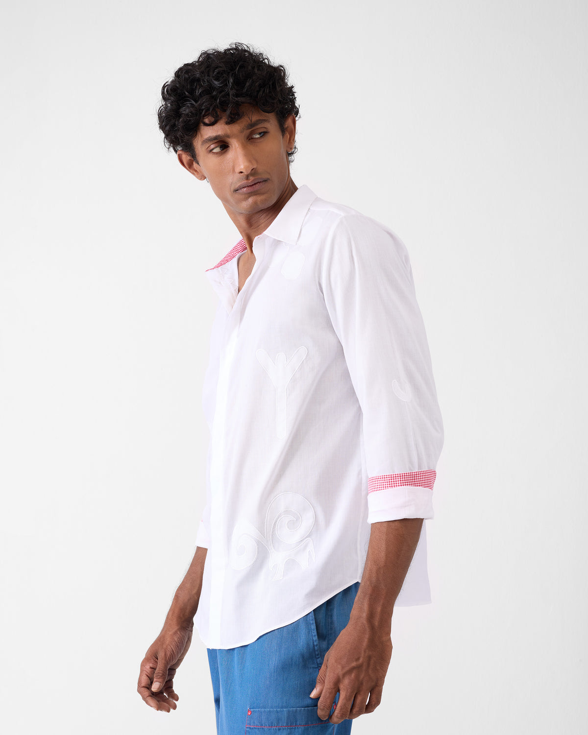 Three-quarter view of a white Hakuna Shirt with tonal appliqués and gingham cuffs.