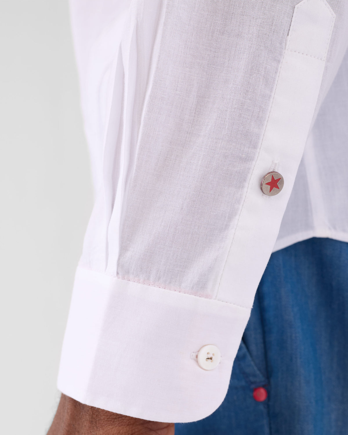 Close-up of a white Hakuna Shirt cuff with a red star button.