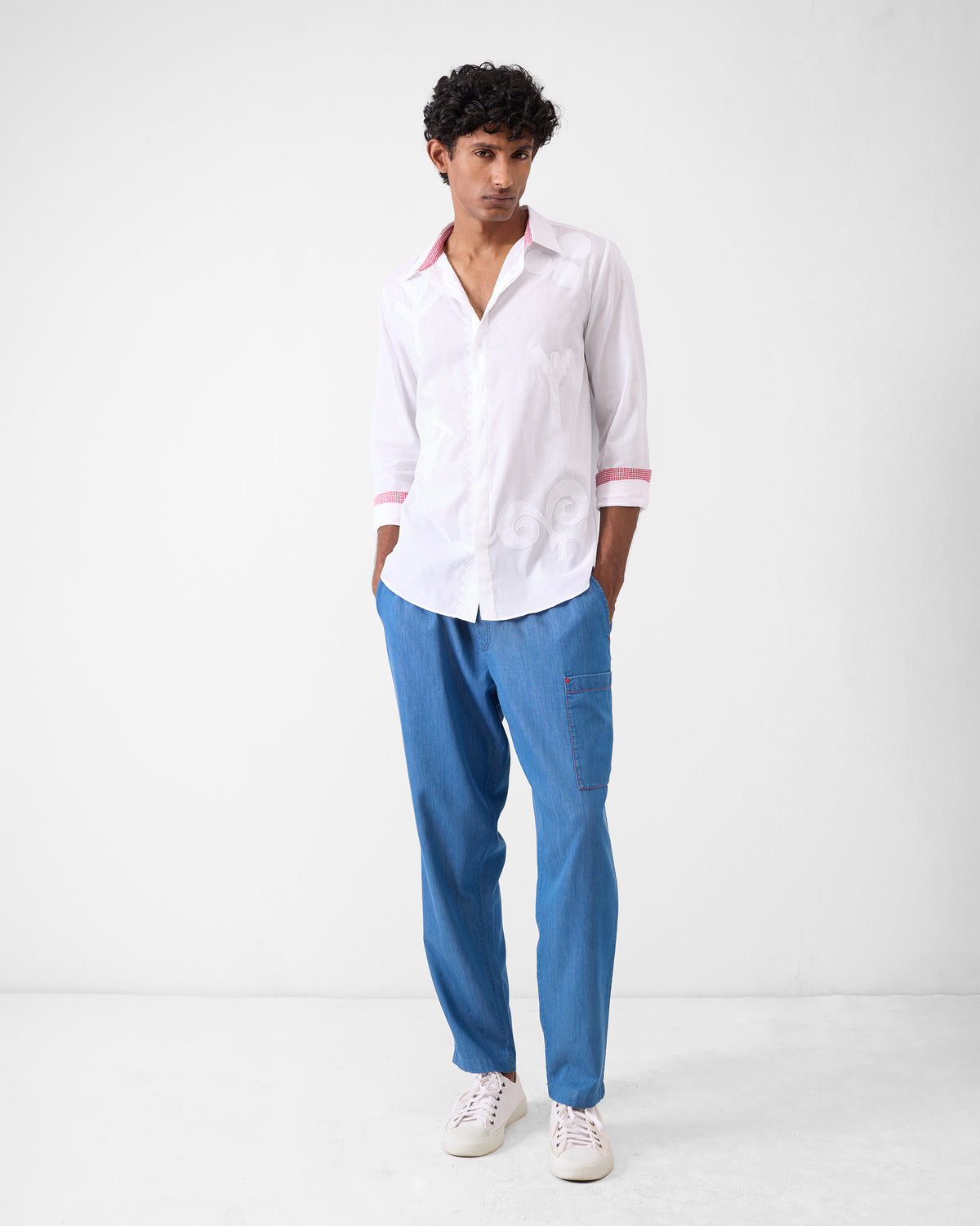 Person wearing a white Hakuna Shirt with tonal motifs and contrast cuffs.