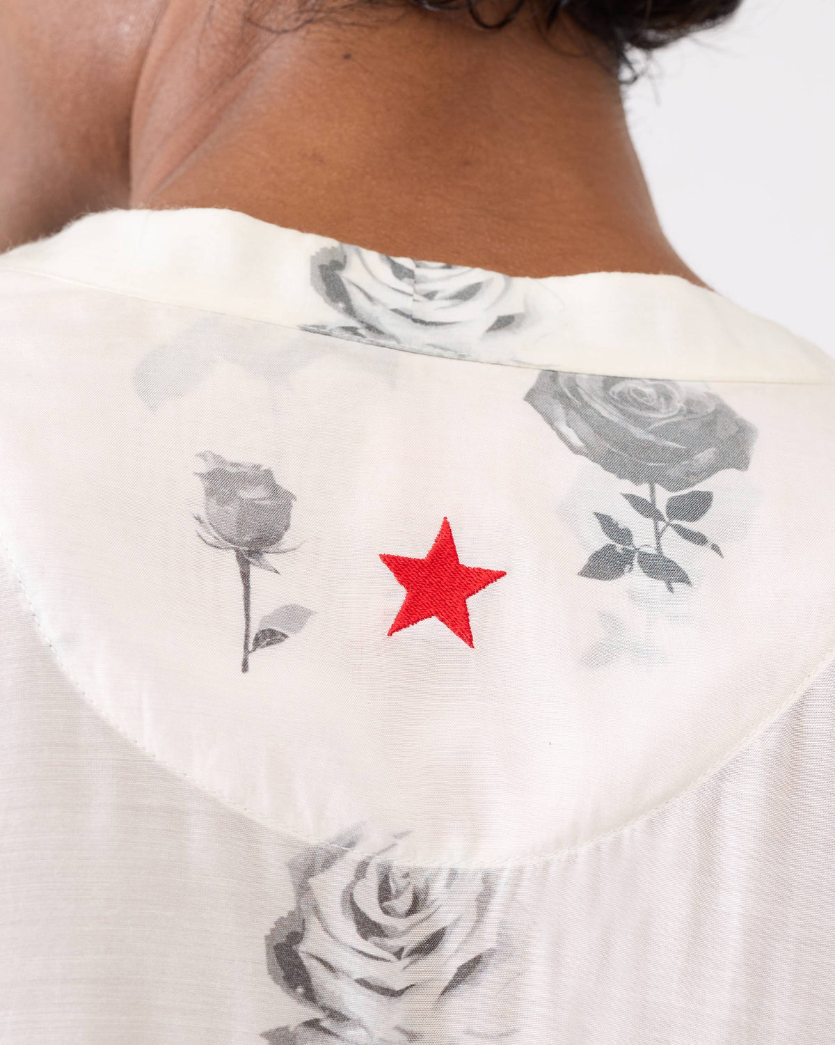 Close-up of a red star on a light grey Astral kurta with rose print.