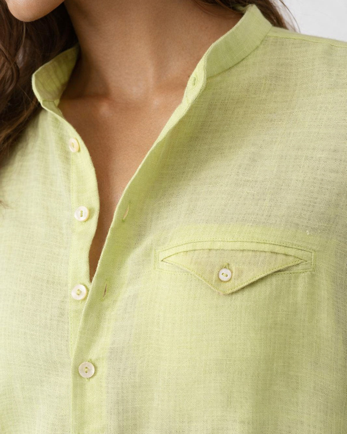 Close-up of a light green Fort kurta placket and flap pocket with white buttons.