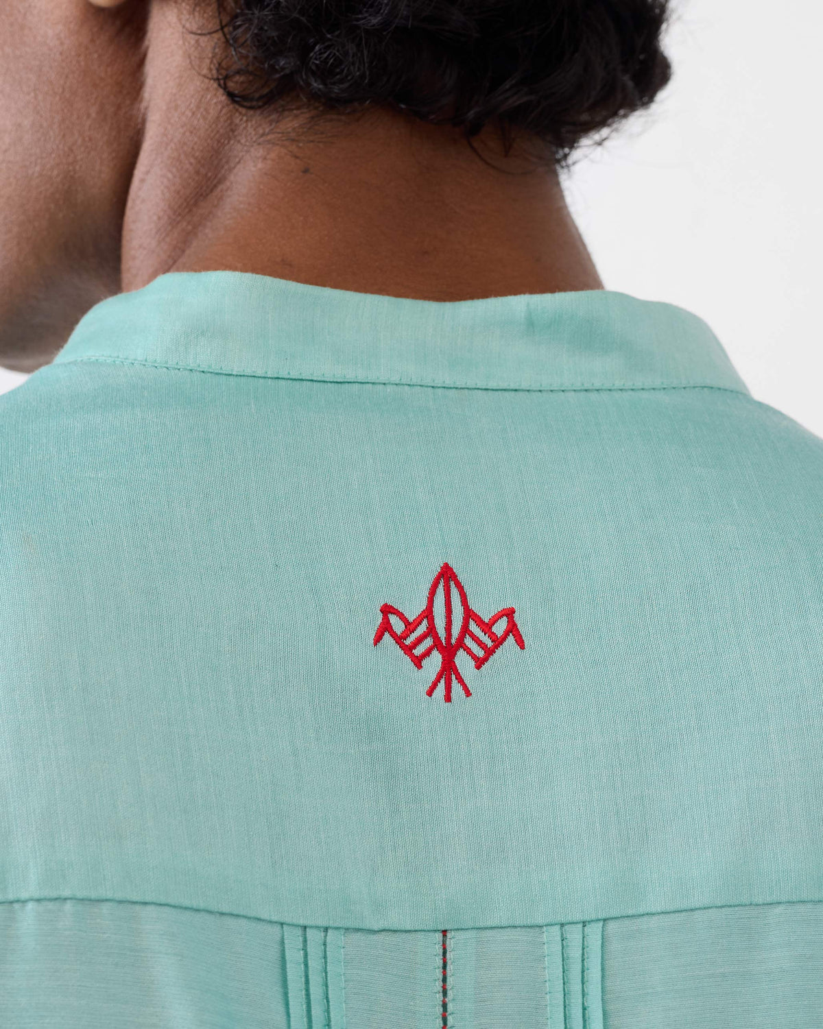 Close-up of a red bird on the back of an aqua Naaz kurta.