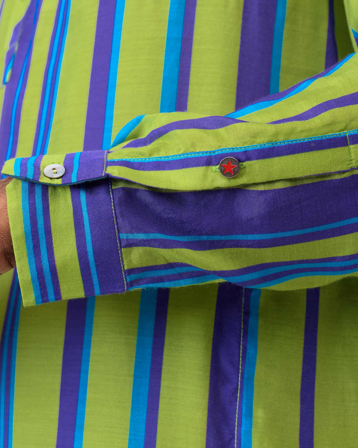 Close-up of a Jashn kurta sleeve showing green blue stripes and a red star button.