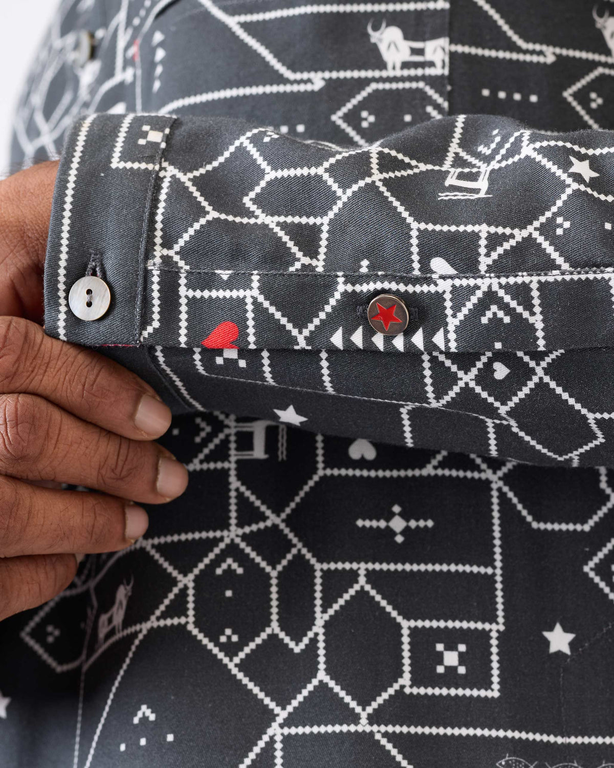 Close-up of a Galle Kurta cuff with a geometric print and red star button.