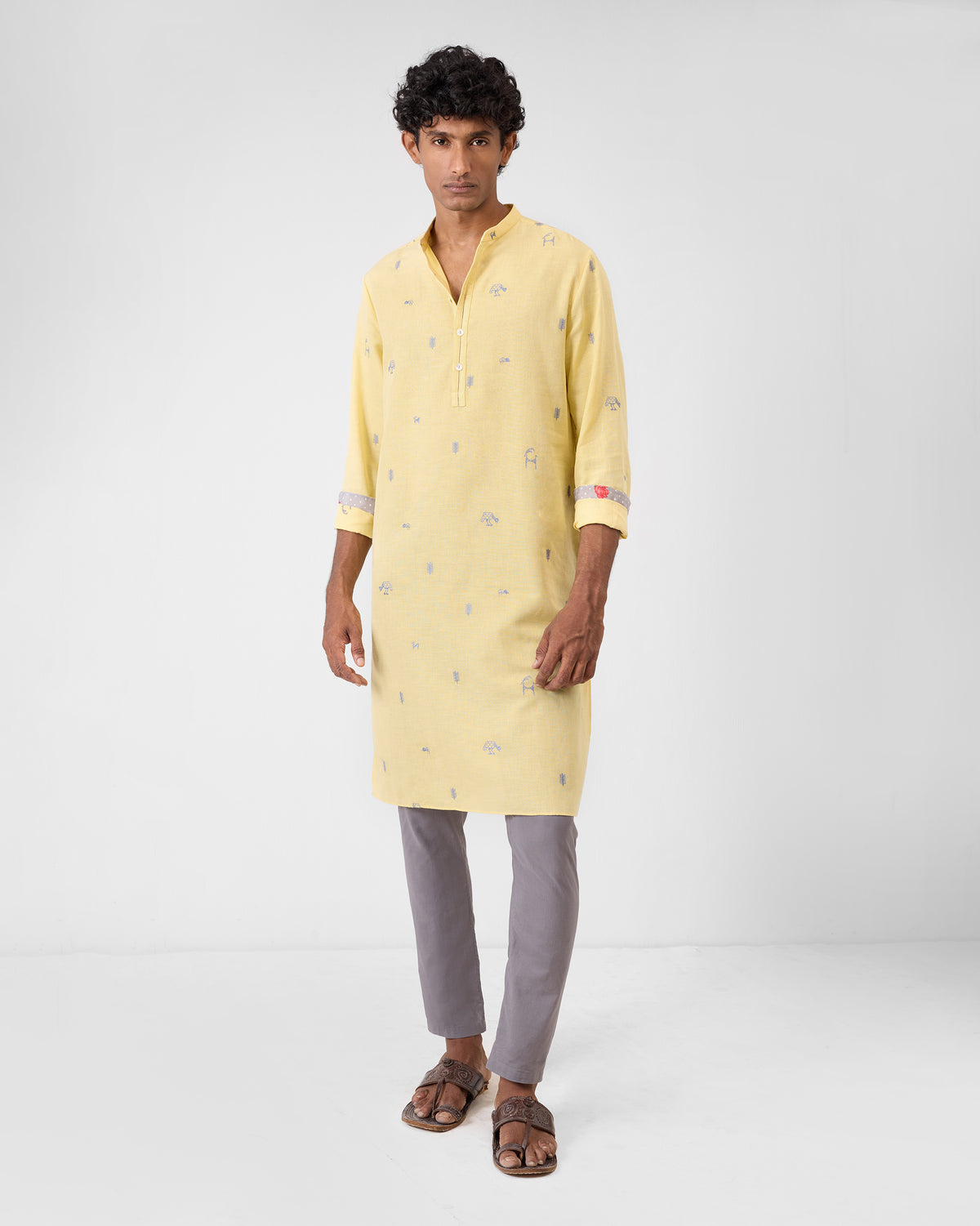 Person wearing a light yellow Astral kurta with grey embroidered icons.