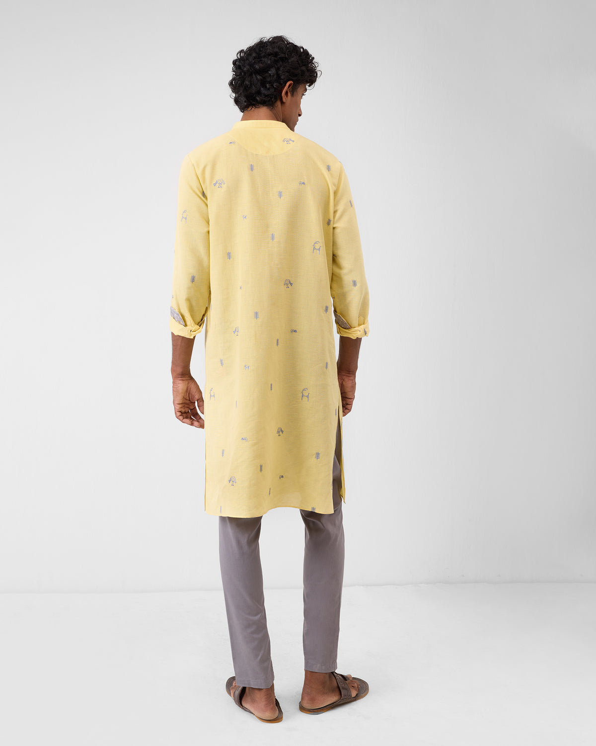Back of a light yellow Astral kurta with grey embroidered icons.