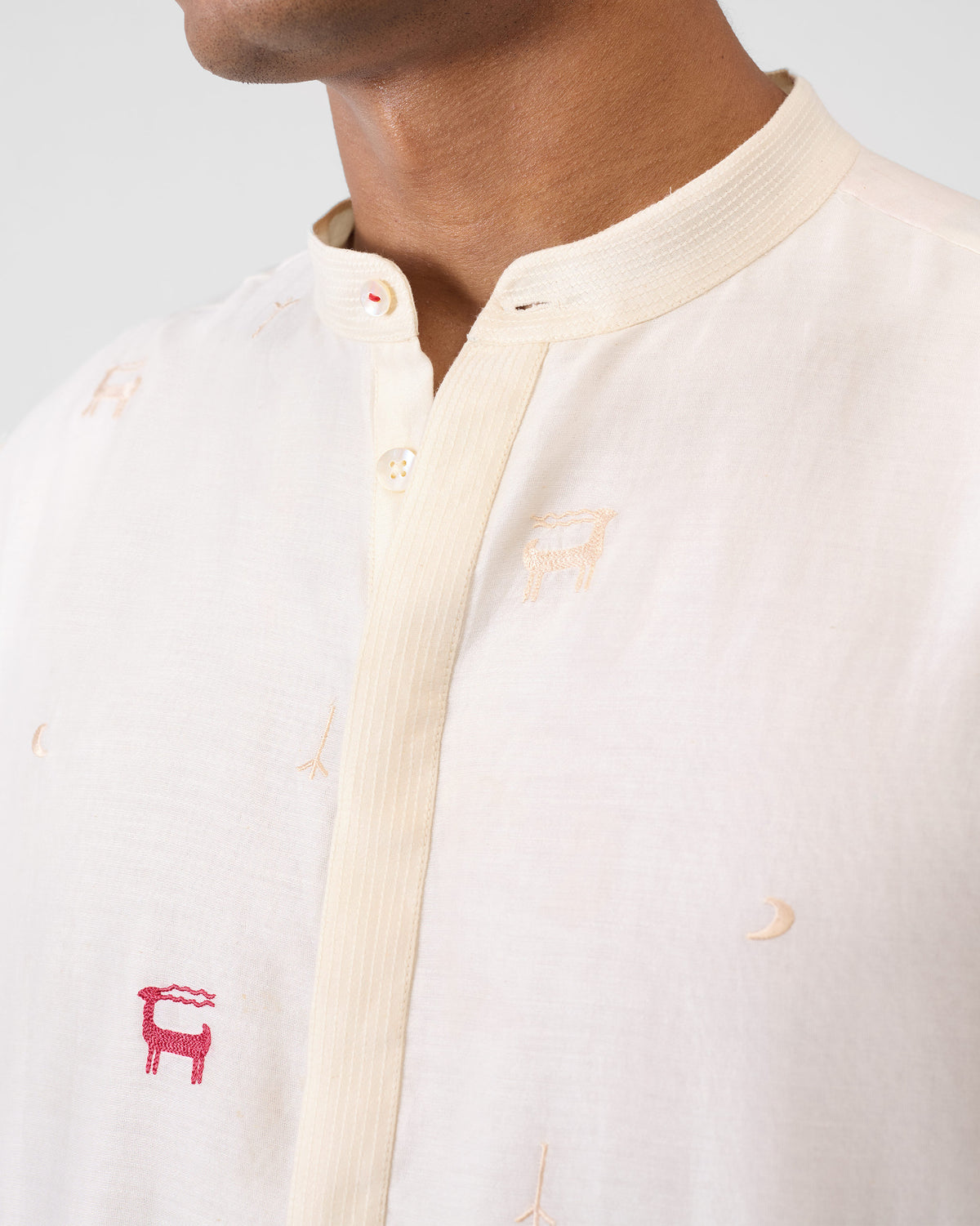 Close-up of an ivory neckband kurta showing red deer embroidery.