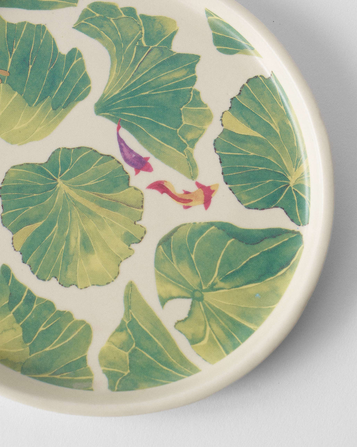 Close-up of Lily Pond plate lily pads with purple and orange fish.