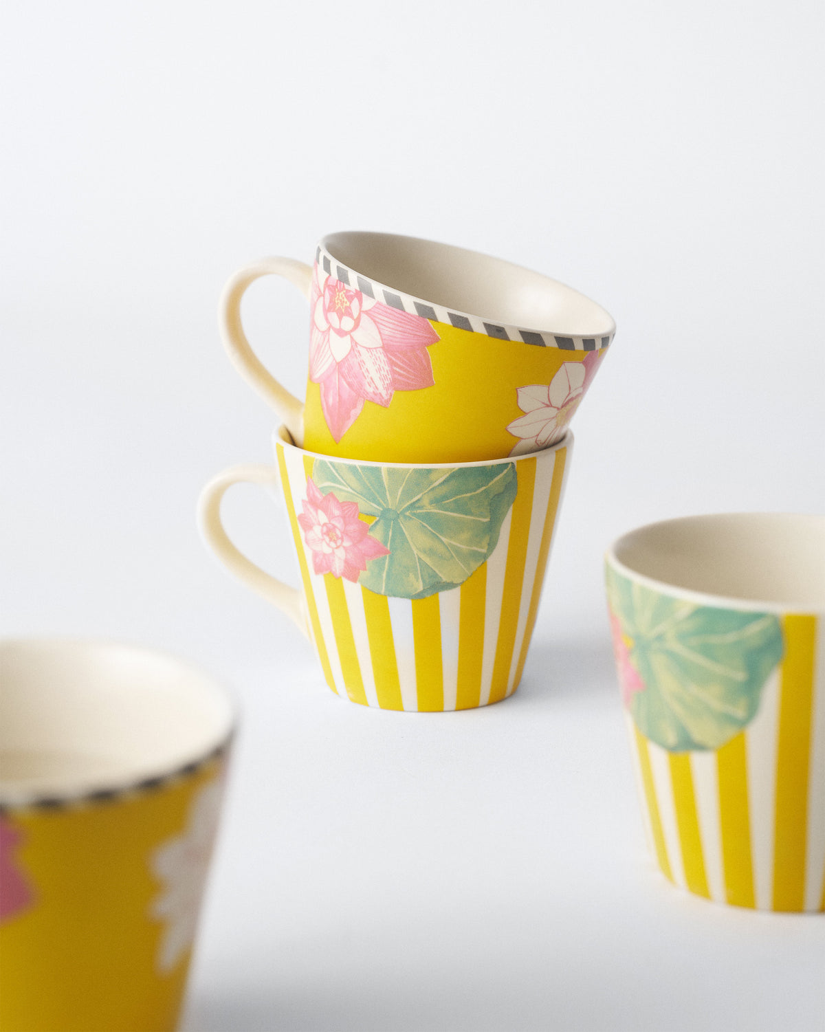 Stacked Lotus Garden espresso mugs in floral and striped designs.