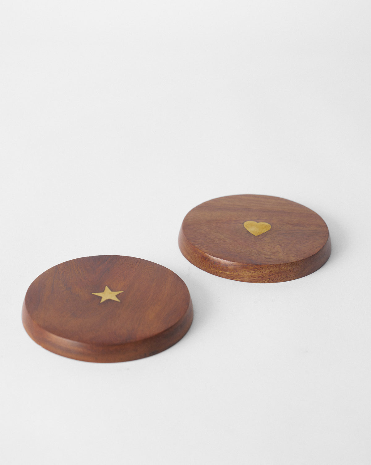 Wooden Aster mug lids showing brass star and heart inlays and beveled edges.