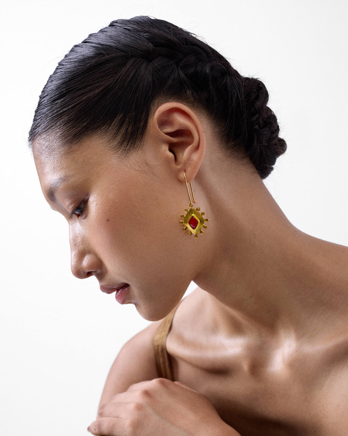 Person wearing a gold garnet barfi drop with red glass.