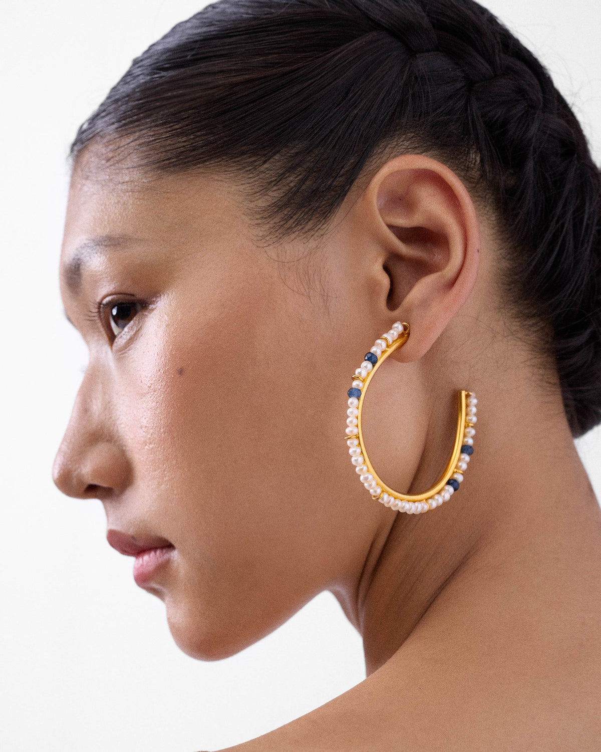 Side profile of a large gold Raja bali with pearls on a person.
