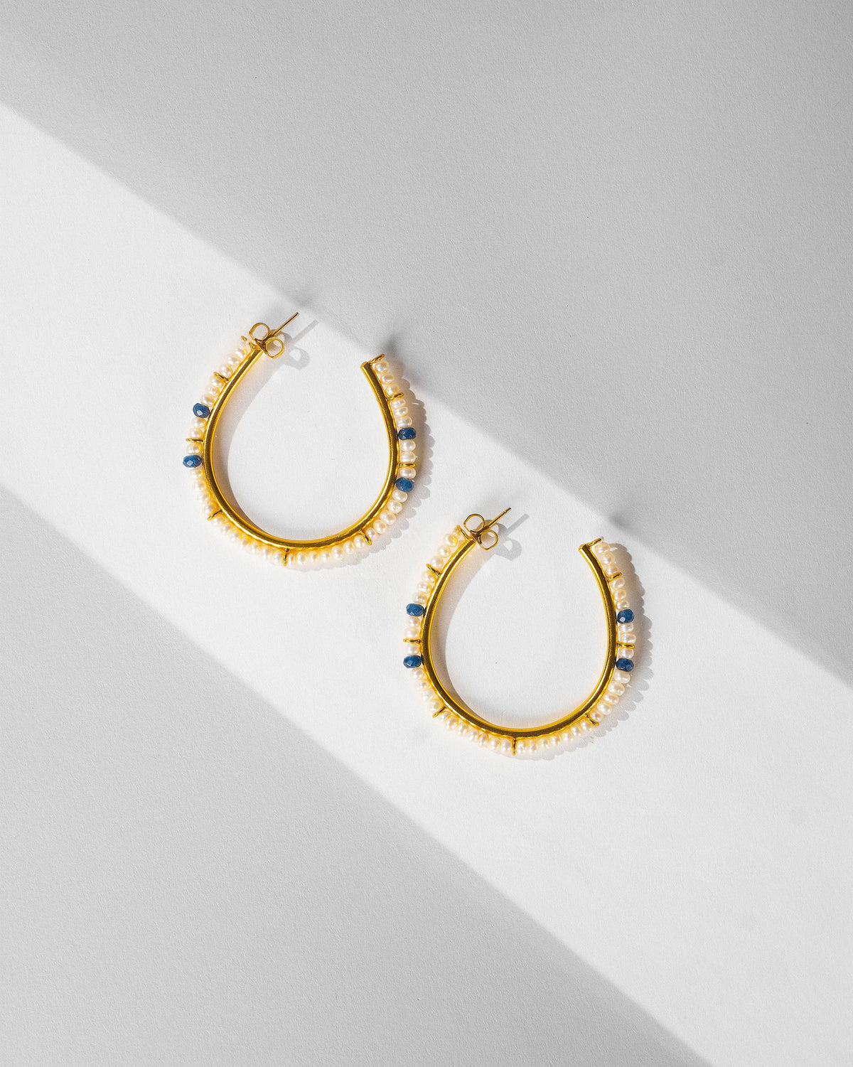 Pair of large gold Raja balis with pearl edges and blue beads.