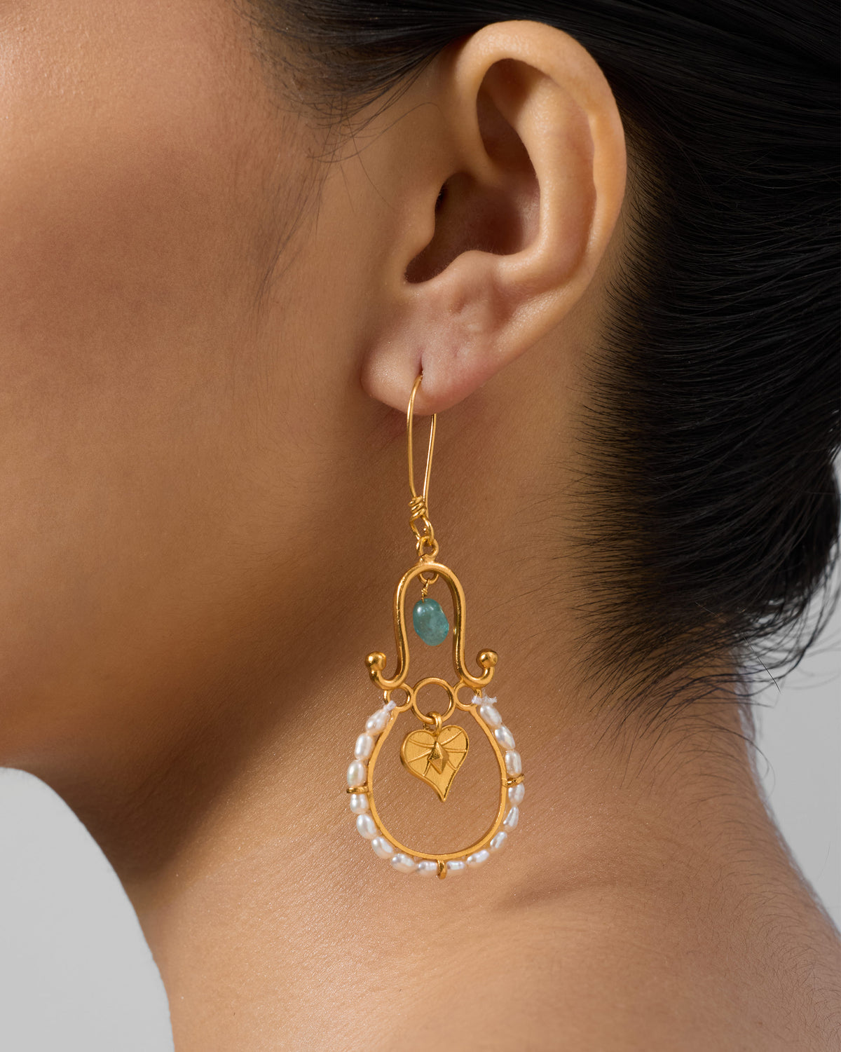 Side profile of a gold Peepal Patta dangler with pearls on a person.