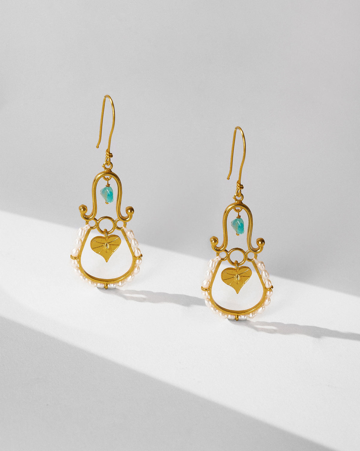 Pair of gold Peepal Patta danglers with turquoise and pearl edges.