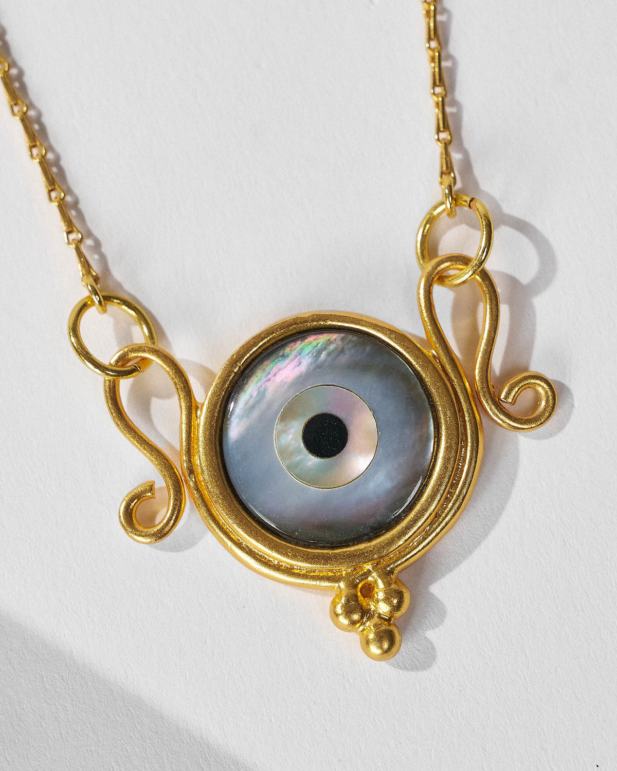 Close-up of Turki Nazar pendant with iridescent eye and gold scrolls.