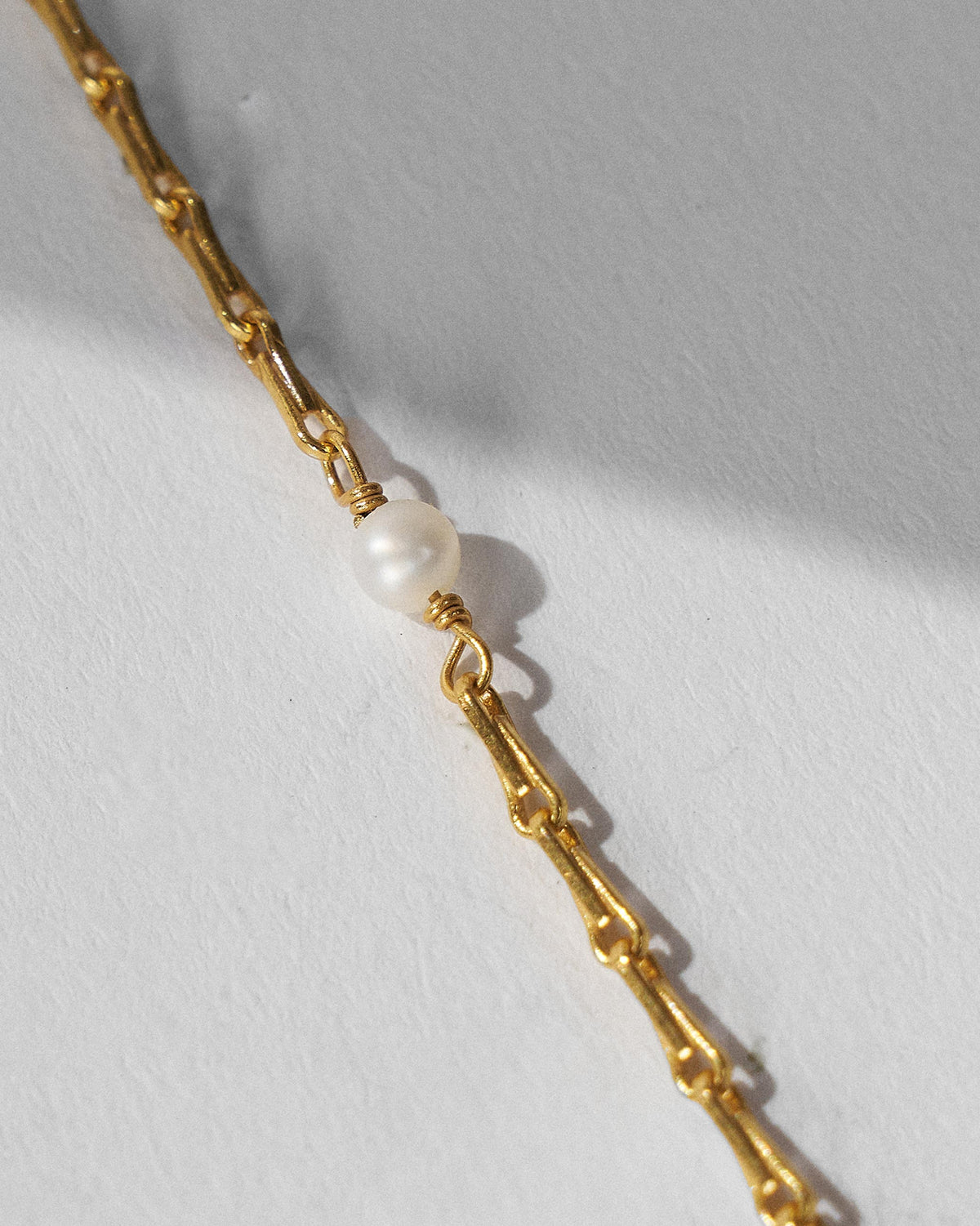 Close-up of Turki Nazar chain links with a wire-wrapped pearl.
