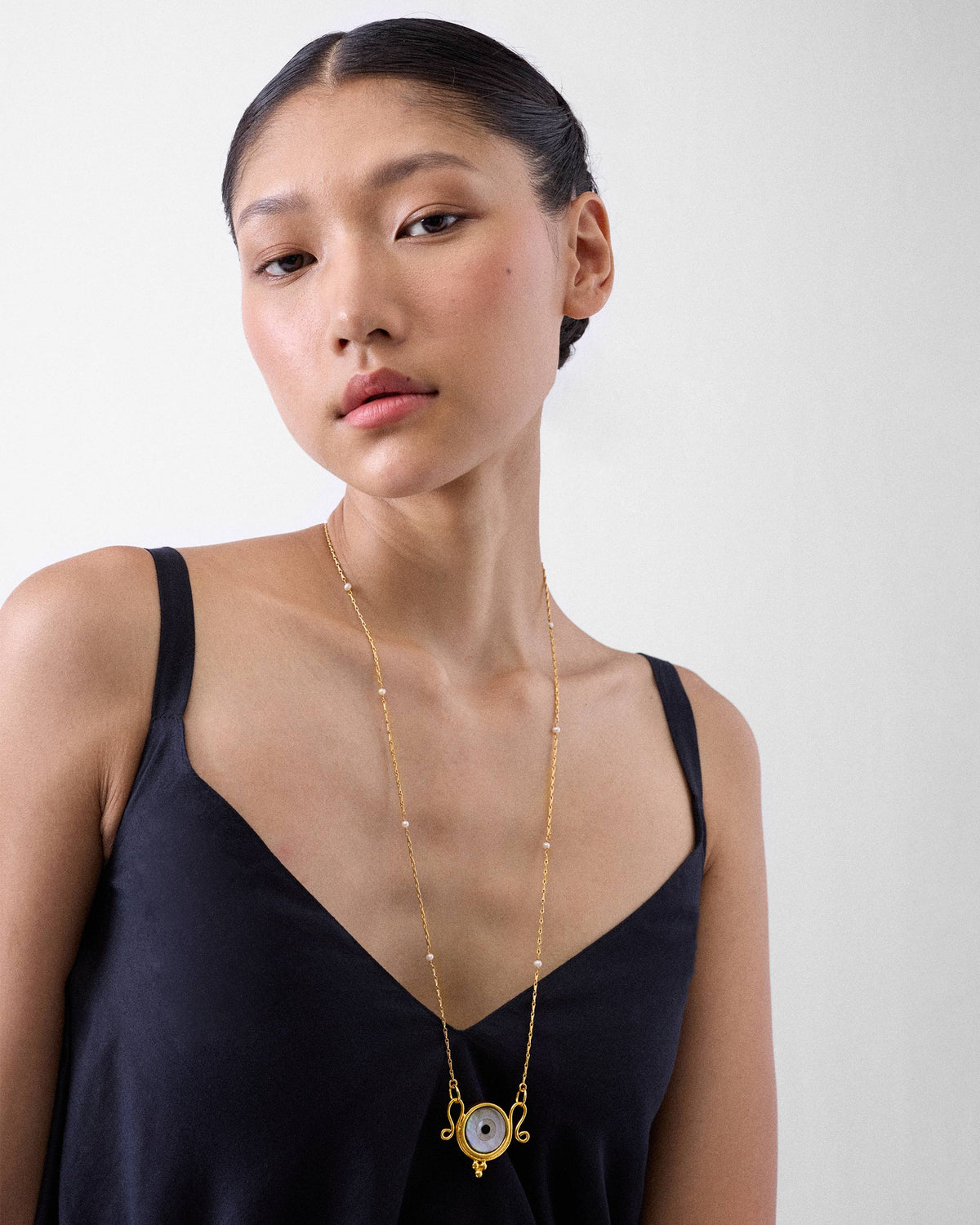 Person wearing a gold Turki Nazar chain with an eye pendant.