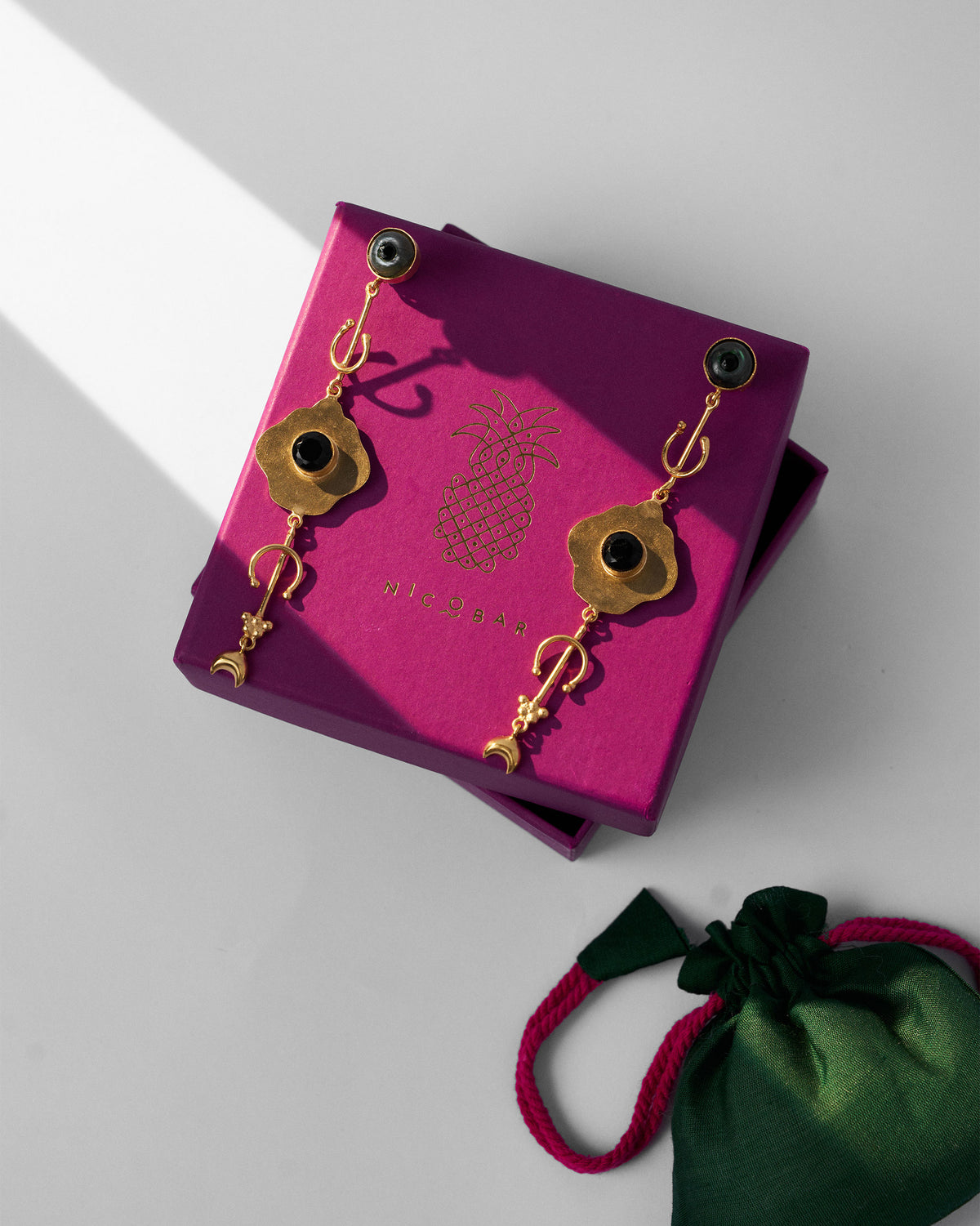 Berber Eye Dangler pair displayed on a magenta gift box.