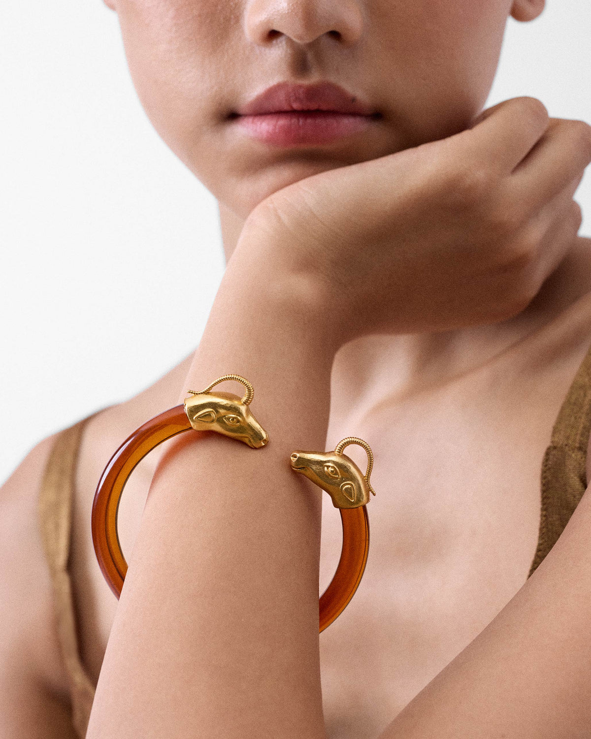 Amber Unicorn bangle with gold animal-head ends worn on a wrist.
