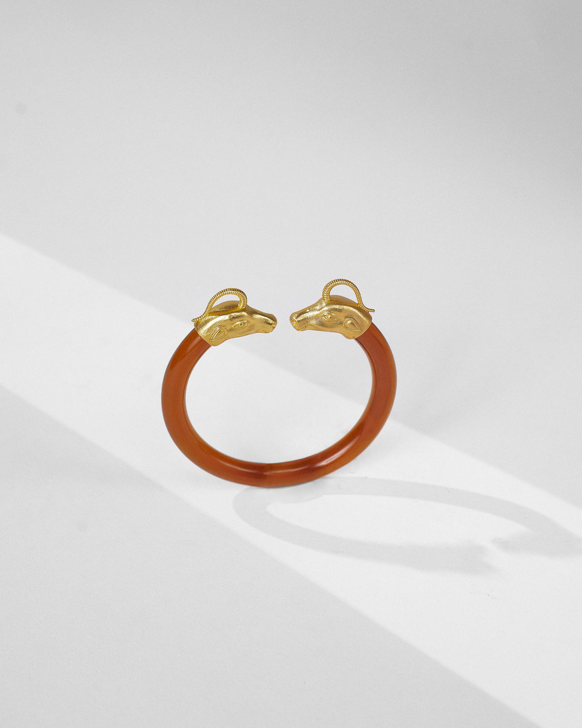 Amber Unicorn open bangle showing gold animal-head ends facing each other.