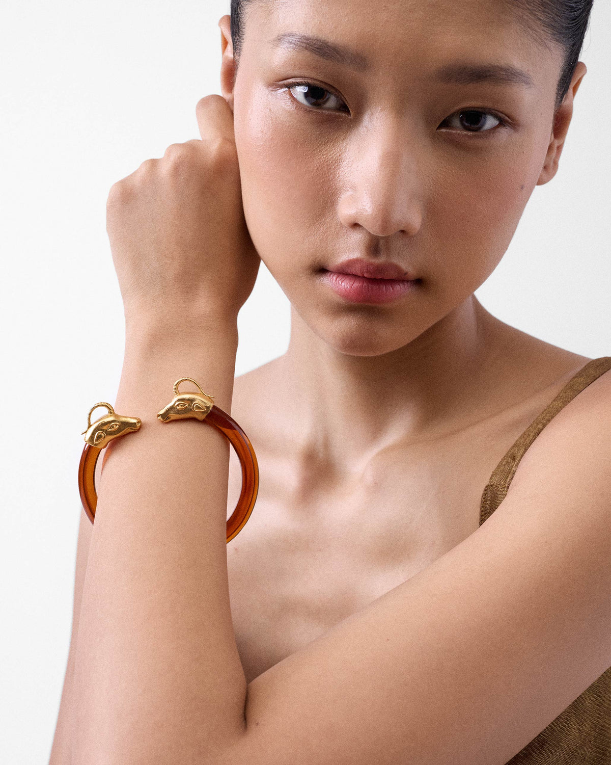 Person wearing an amber Unicorn bangle with gold animal-head ends.