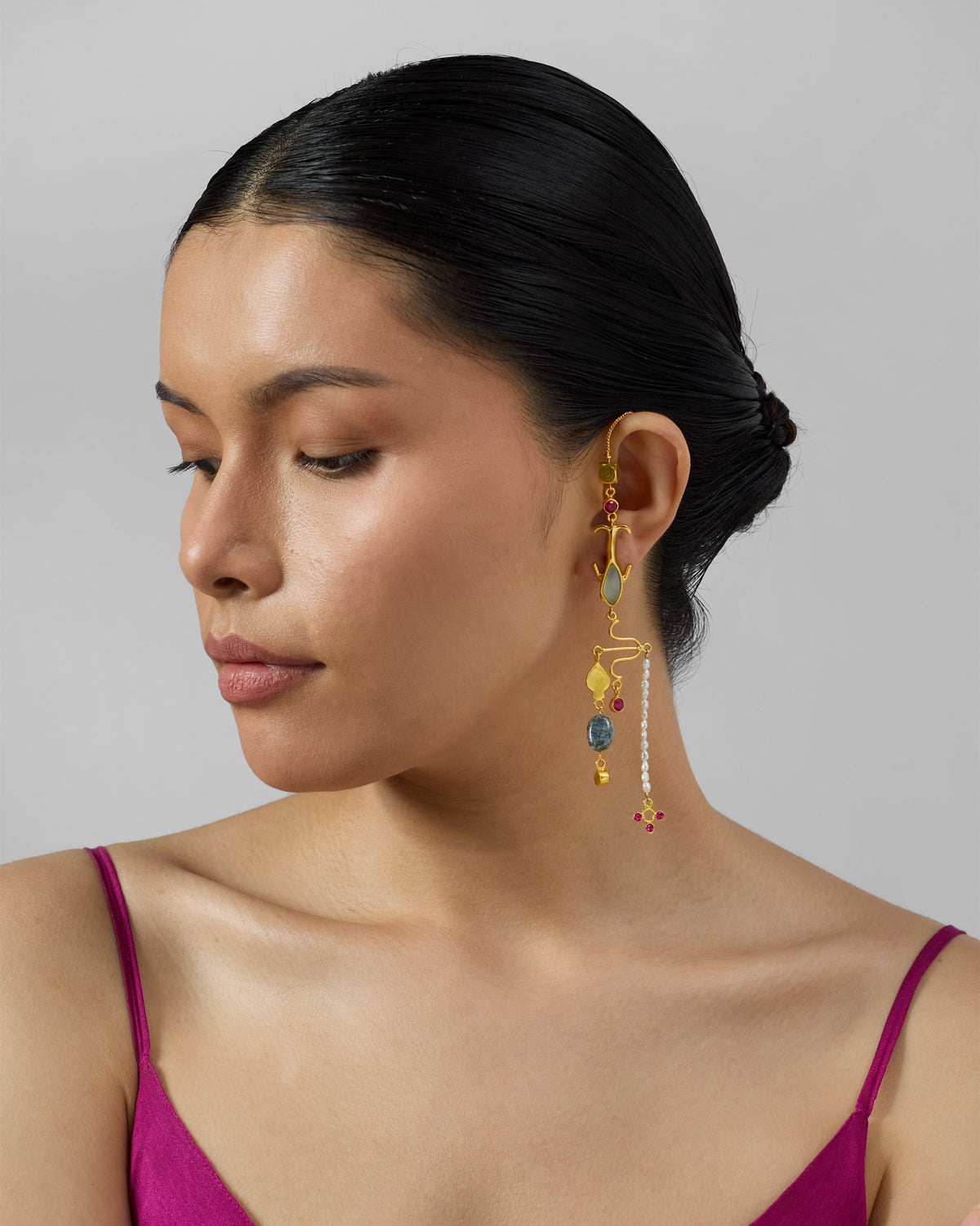 Person wearing a long gold Indus dangler with stones and pearls.