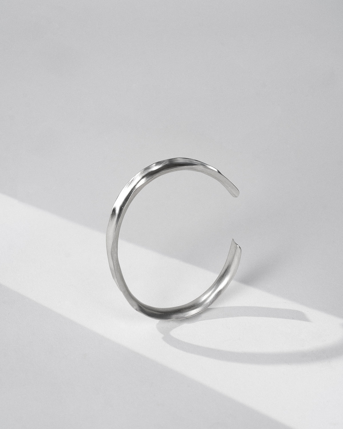 Side view of a thin silver Batur cuff with an undulating band.