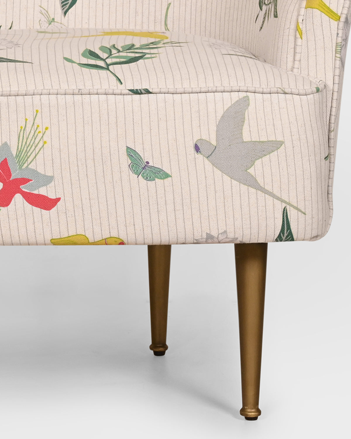 Close-up of Canopy Chair upholstery with grey birds, red flowers and brass legs.